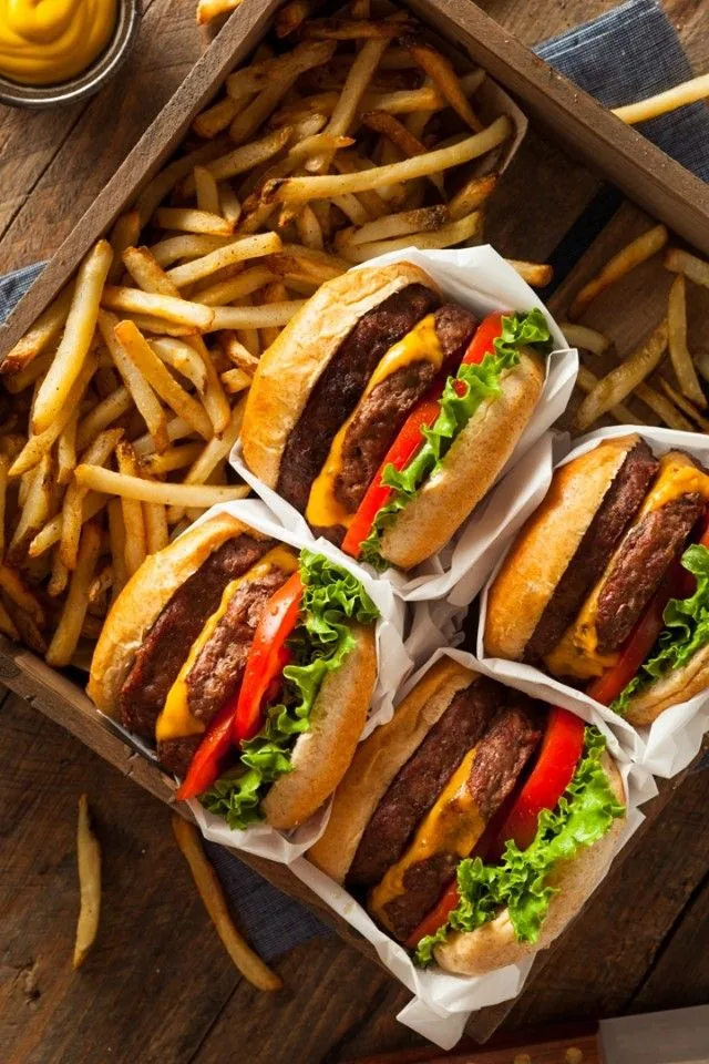 Quatro hambúrgueres com batata frita numa caixa de madeira